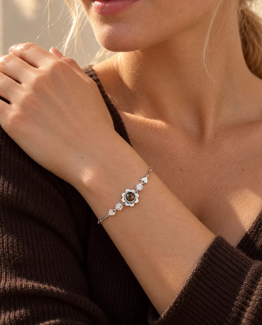 Vrouw met haar hand op haar schouder draagt de zilverkleurige armband met klavertjesbloem