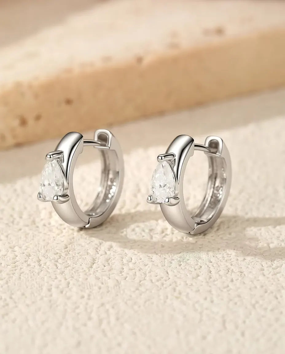 Moissanite Oorbellen in 925 Sterling Zilver - het paar naast elkaar rechtop op een licht gestructureerd oppervlak