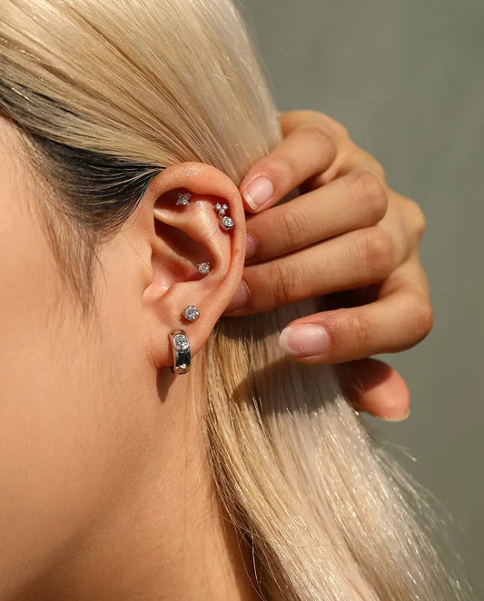 Moissanite Huggie Creolen in 925 Sterling Zilver - gedragen door een model dat haar haar achter haar oor strijkt