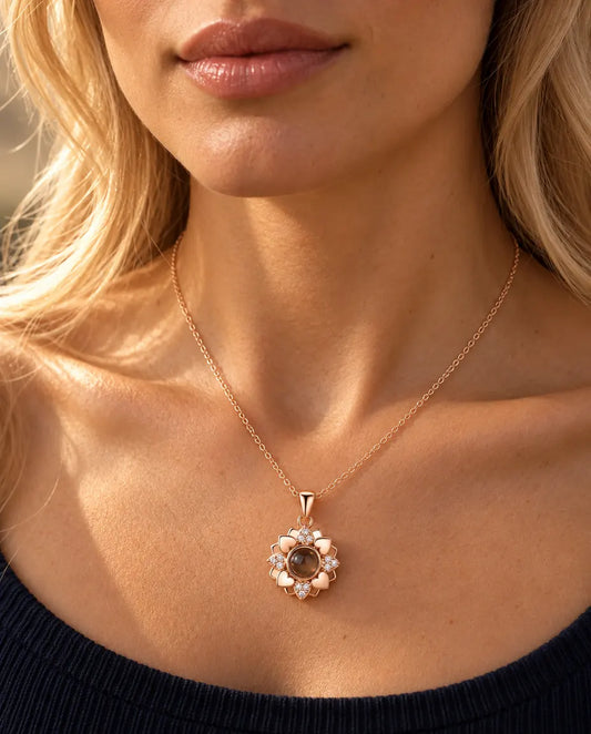 Vrouw in een donkerblauwe gebreide top draagt de roségoudkleurige ketting met bloem van hartjes
