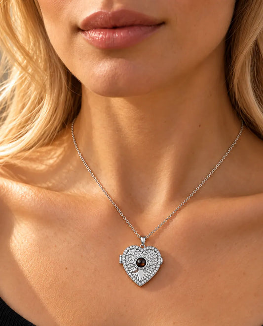 Vrouw in een zwarte gebreide top draagt de zilverkleurige ketting met hartmedaillon, levensboom en projectiesteentje