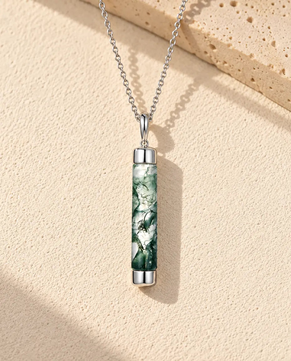 Mosagaat Ketting met Lange Cilinder in 925 Sterling Zilver - liggend op een licht gestructureerd oppervlak naast een blok travertijn