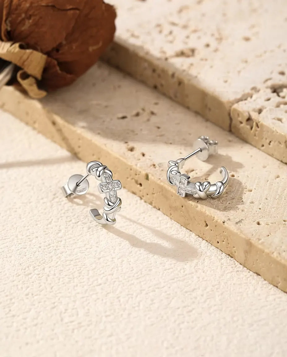 Moissanite Creolen met Kruisje in 925 Sterling Zilver - het paar naast elkaar op een licht gestructureerd oppervlak