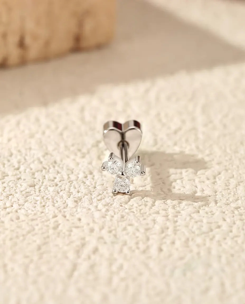 Moissanite Oorknopjes Klavertje in 925 Sterling Zilver - rechtop op het hartvormige achterkantje, op een licht gestructureerd oppervlak