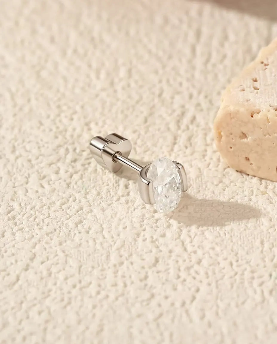 Moissanite Oorknopjes Ovaal in Zijzetting - op zijn kant op een licht gestructureerd oppervlak, hartvormig achterkantje op de stift