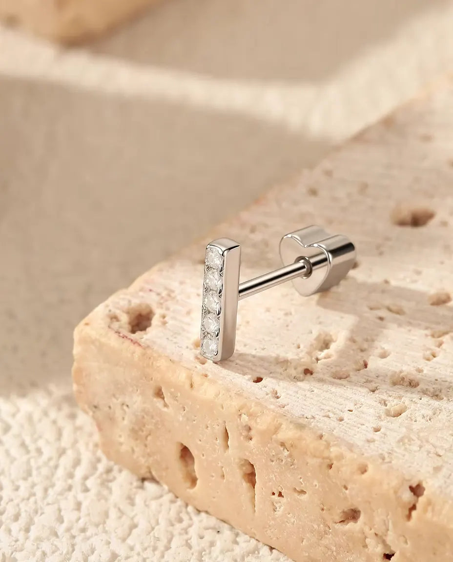 Moissanite Oorknopjes Staafje met Vijf Stenen in 925 Sterling Zilver - op de rand van een travertijnplaat