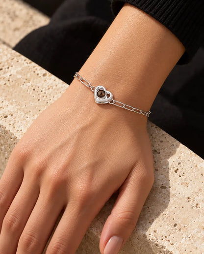 Vrouw draagt de zilverkleurige armband met dubbel hart en foto erin om haar pols in warm zonlicht