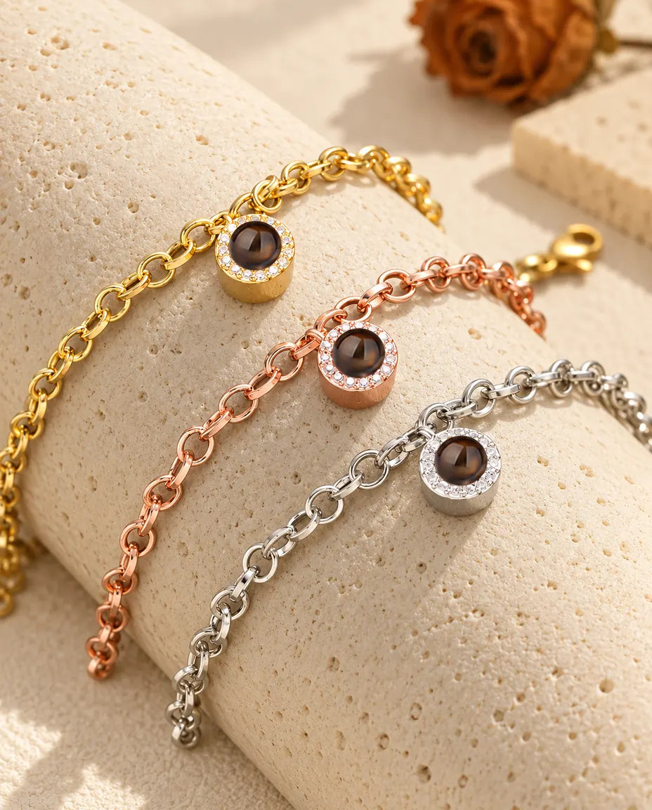 Goudkleurige, roségoudkleurige en zilverkleurige armbanden met rond zirkonia-bedeltje over een blok travertijn