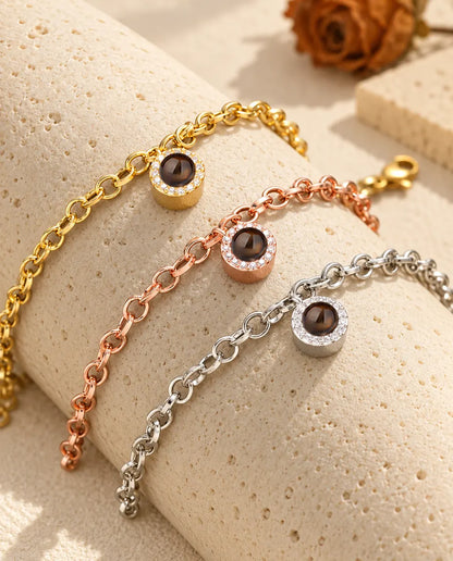 Goudkleurige, roségoudkleurige en zilverkleurige armbanden met rond zirkonia-bedeltje over een blok travertijn