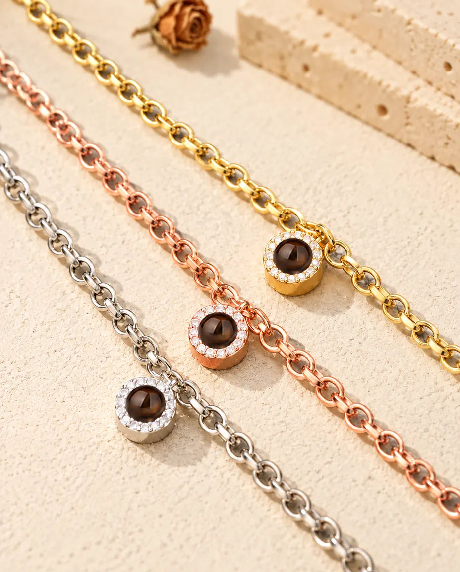 Close-up van drie armbanden met rond zirkonia-bedeltje in goudkleurig, roségoudkleurig en zilverkleurig