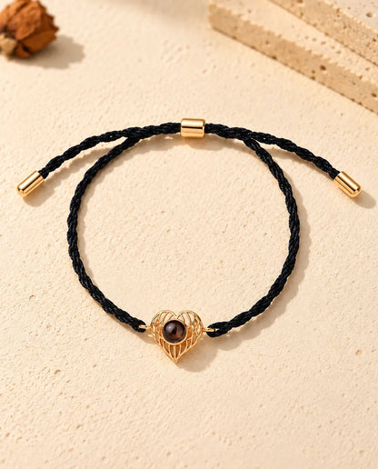 Bovenaanzicht van de goudkleurige armband met foto erin en engelenvleugelhart, met het verstelbare schuifje