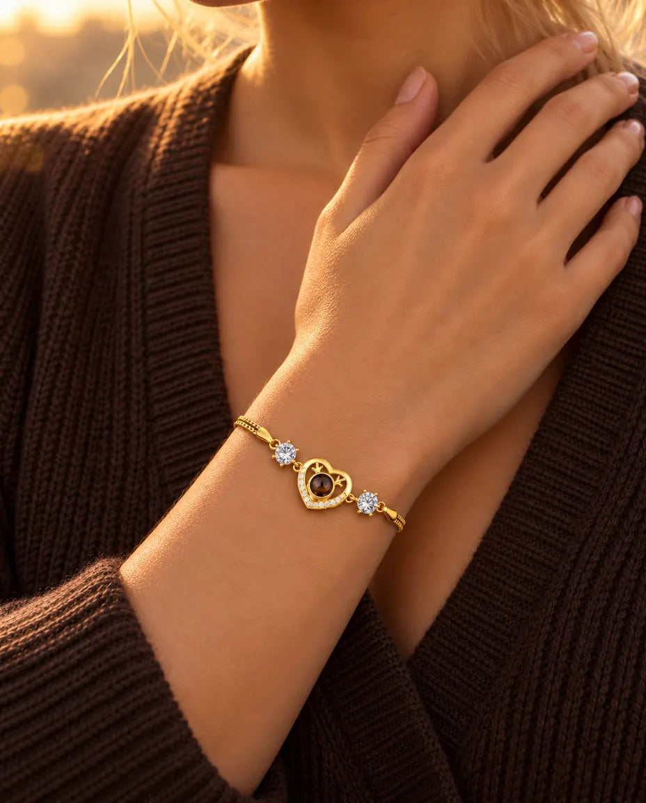 Close-up van de goudkleurige geweihartjesarmband met zirkonia om een pols die bij het sleutelbeen rust