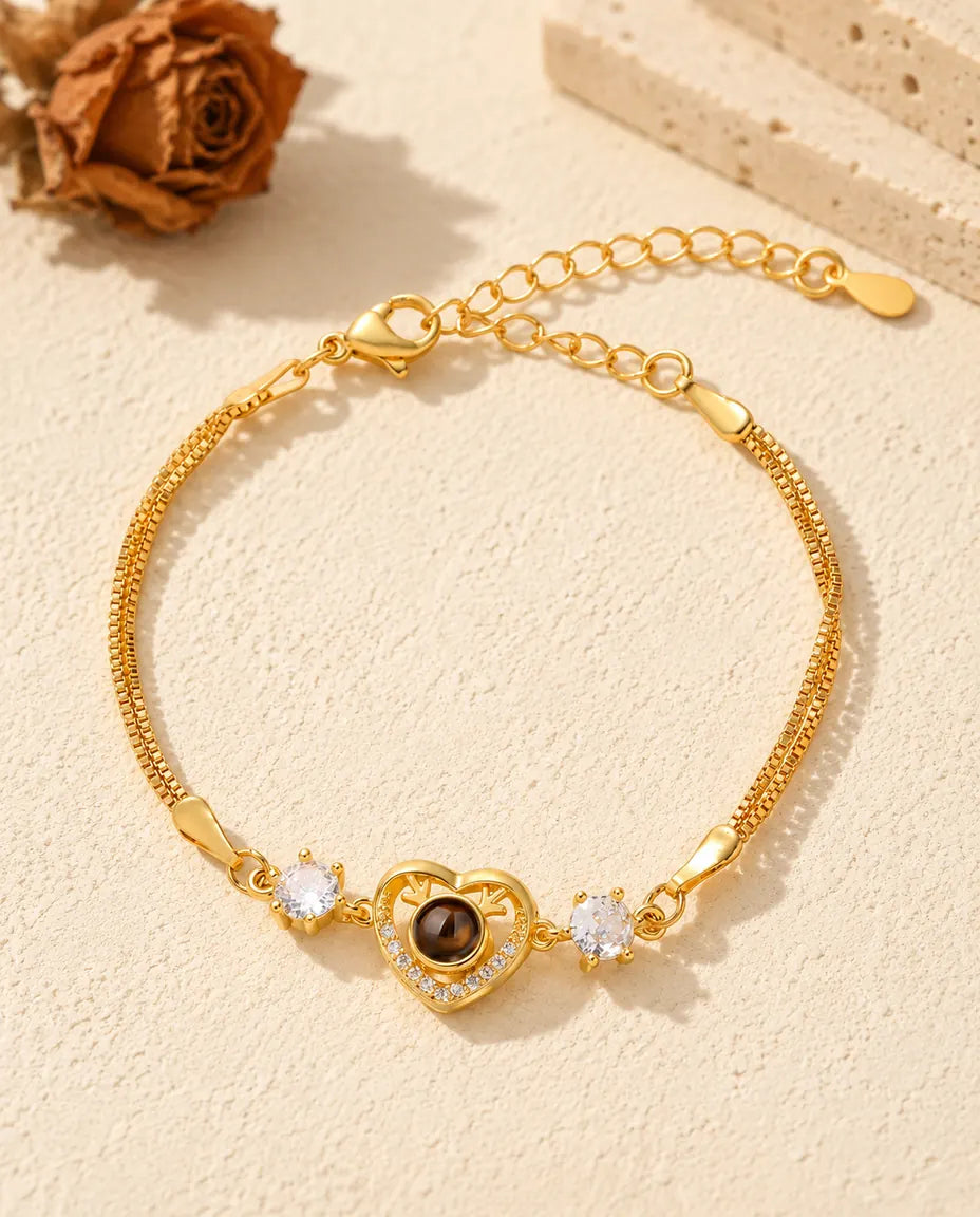 Bovenaanzicht van de goudkleurige armband met foto erin en geweihartje, met de verlengketting erbij