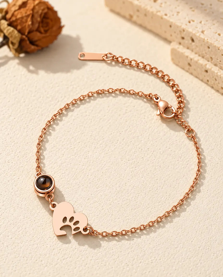 Roségoudkleurige armband met pootafdrukhartje, rond projectiesteentje en karabijnsluiting