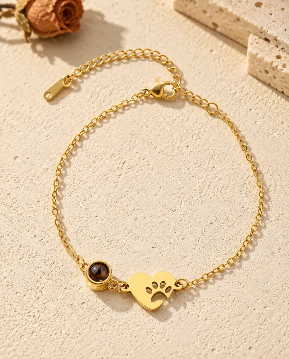 Bovenaanzicht van de goudkleurige armband met foto erin en het hartje met pootafdruk