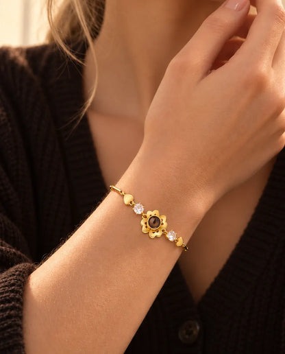 Close-up van de goudkleurige klavertjesarmband met hartjesschakels om een pols vlak bij haar kaak