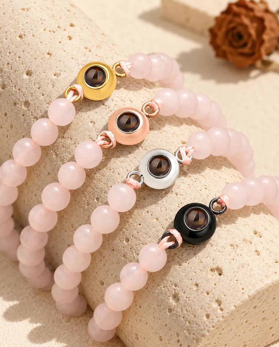 Lichtroze kralenarmbanden met foto erin, met een goudkleurige, roségoudkleurige, zilverkleurige en zwarte bedel