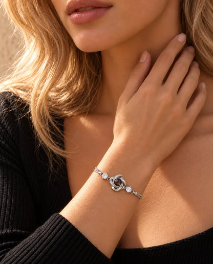Vrouw raakt de zijkant van haar hals aan en draagt de zilverkleurige armband met liefdesknoop