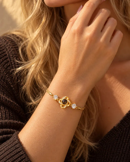 Close-up van de goudkleurige armband met liefdesknoop en zirkonia om een pols vlak bij haar kaak