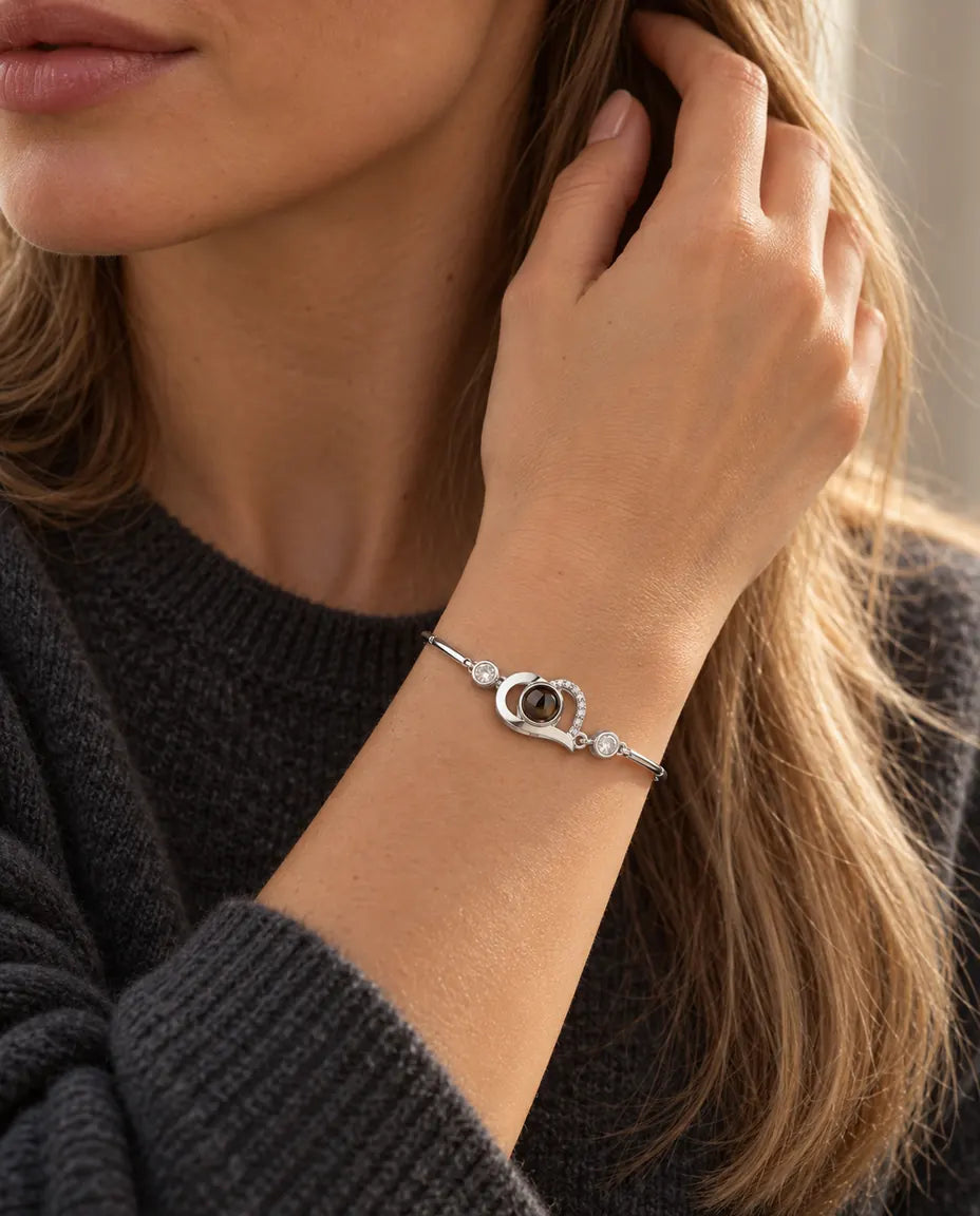Vrouw strijkt met haar hand door haar haar en draagt de zilverkleurige armband met open hartje