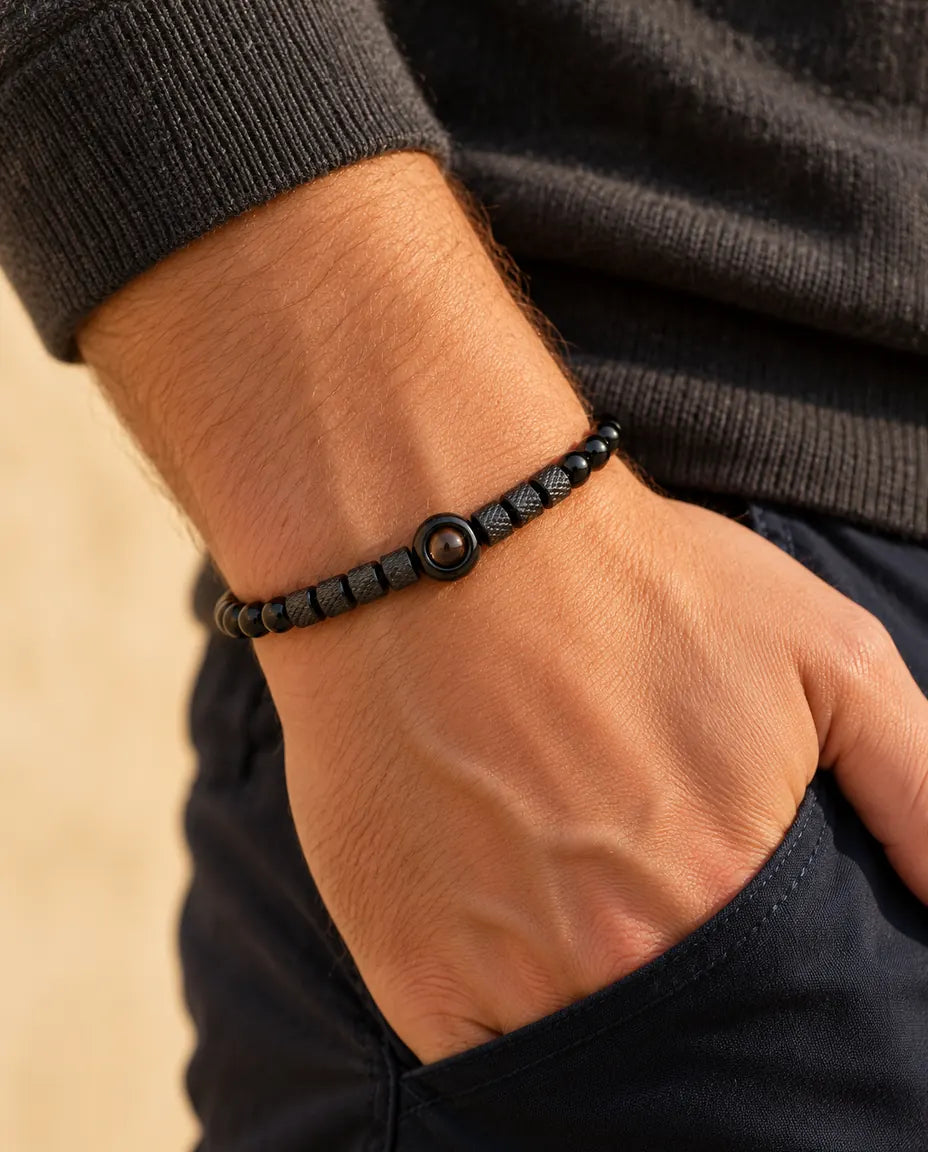 Man draagt de zwarte kralenarmband met foto erin, met zijn hand in zijn broekzak gestoken