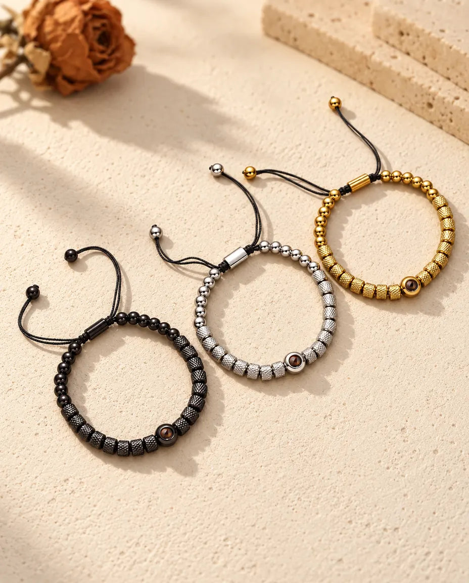 Drie kralenarmbanden met foto erin in goudkleurig, zilverkleurig en zwart naast elkaar