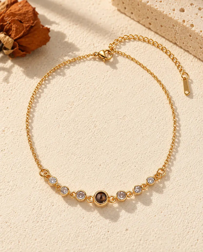 Bovenaanzicht van de goudkleurige armband met foto erin en zirkonia, met de verlengketting erbij