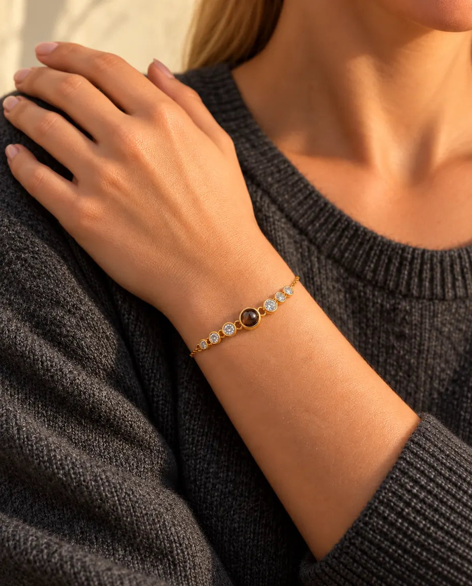 Close-up van de goudkleurige armband met zirkonia om een pols, met haar hand rustend op haar schouder