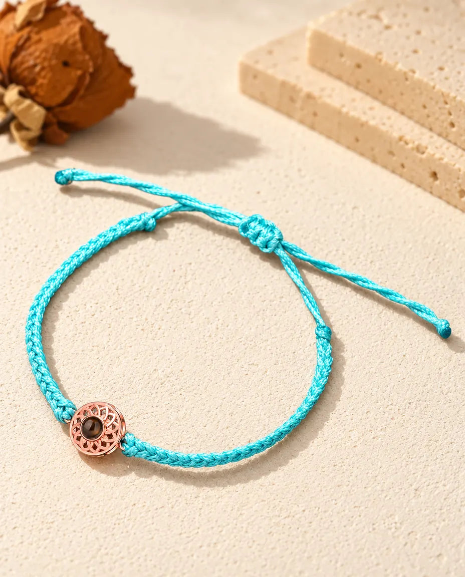 Roségoudkleurige ronde bedel aan een blauw, dun gevlochten koord met verstelbare schuifknoop