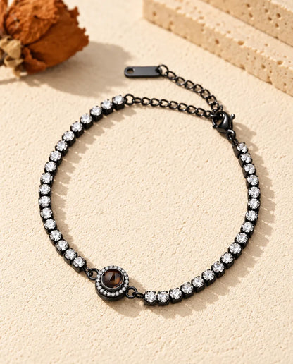 Zwarte tennisarmband met heldere zirkonia en een halo-bedel met projectiesteentje