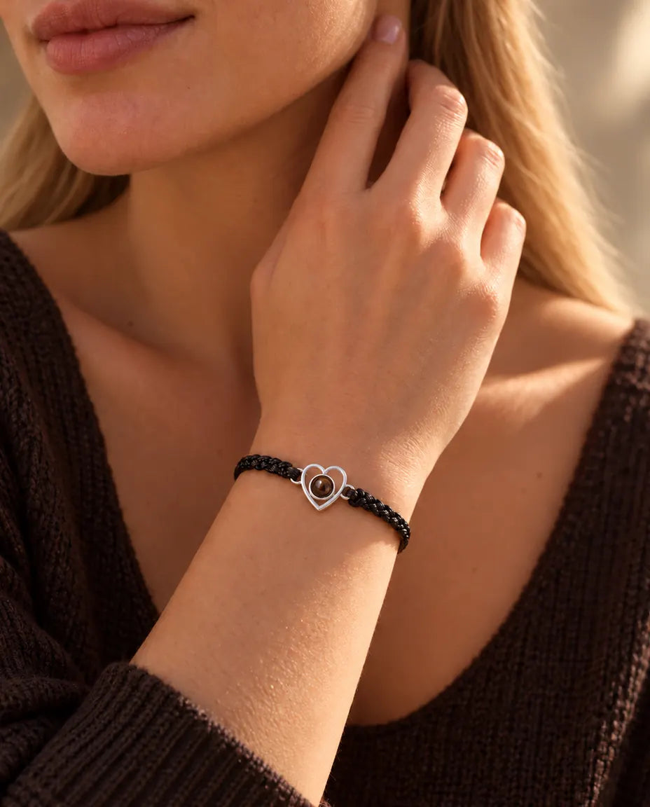 Vrouw met haar vingertoppen langs de hals draagt de armband met zilveren open hartje aan een zwart koord