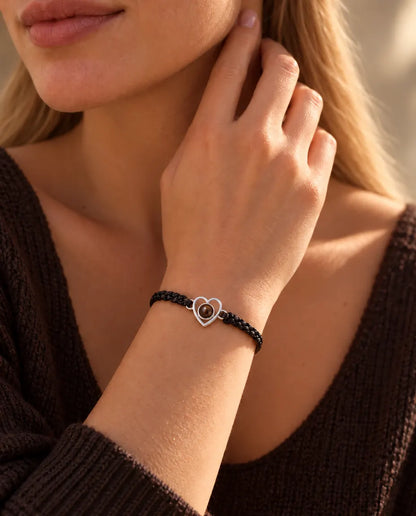 Vrouw met haar vingertoppen langs de hals draagt de armband met zilveren open hartje aan een zwart koord