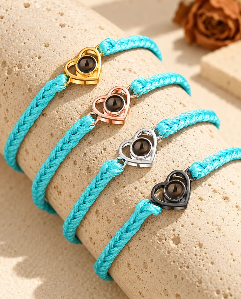 Vier blauwe gevlochten armbanden met goudkleurig, roségoudkleurig, zilveren en zwart open hartje op travertijn
