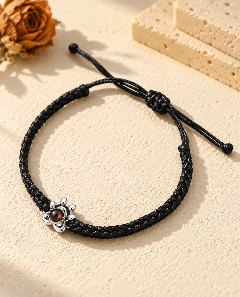 Armband met foto erin: pootje van 925 sterling zilver aan een zwart gevlochten koord, op crèmekleurig gips