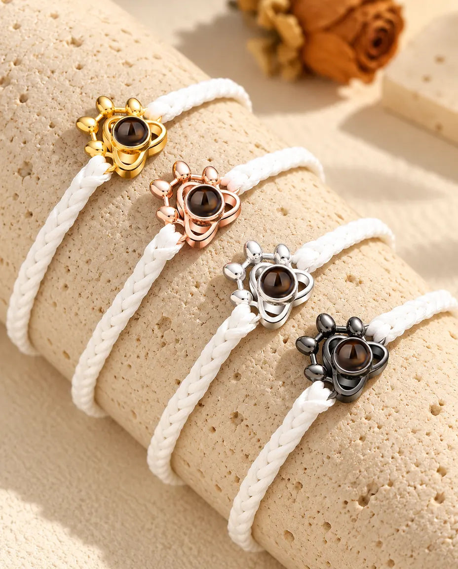 Witte gevlochten armbanden met pootje, op een rij in elke bedelkleur