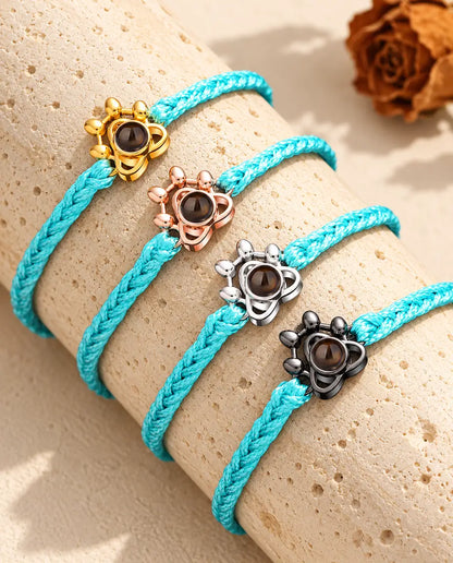 Vier blauwe gevlochten armbanden met goudkleurig, roségoudkleurig, zilveren en zwart pootje op travertijn