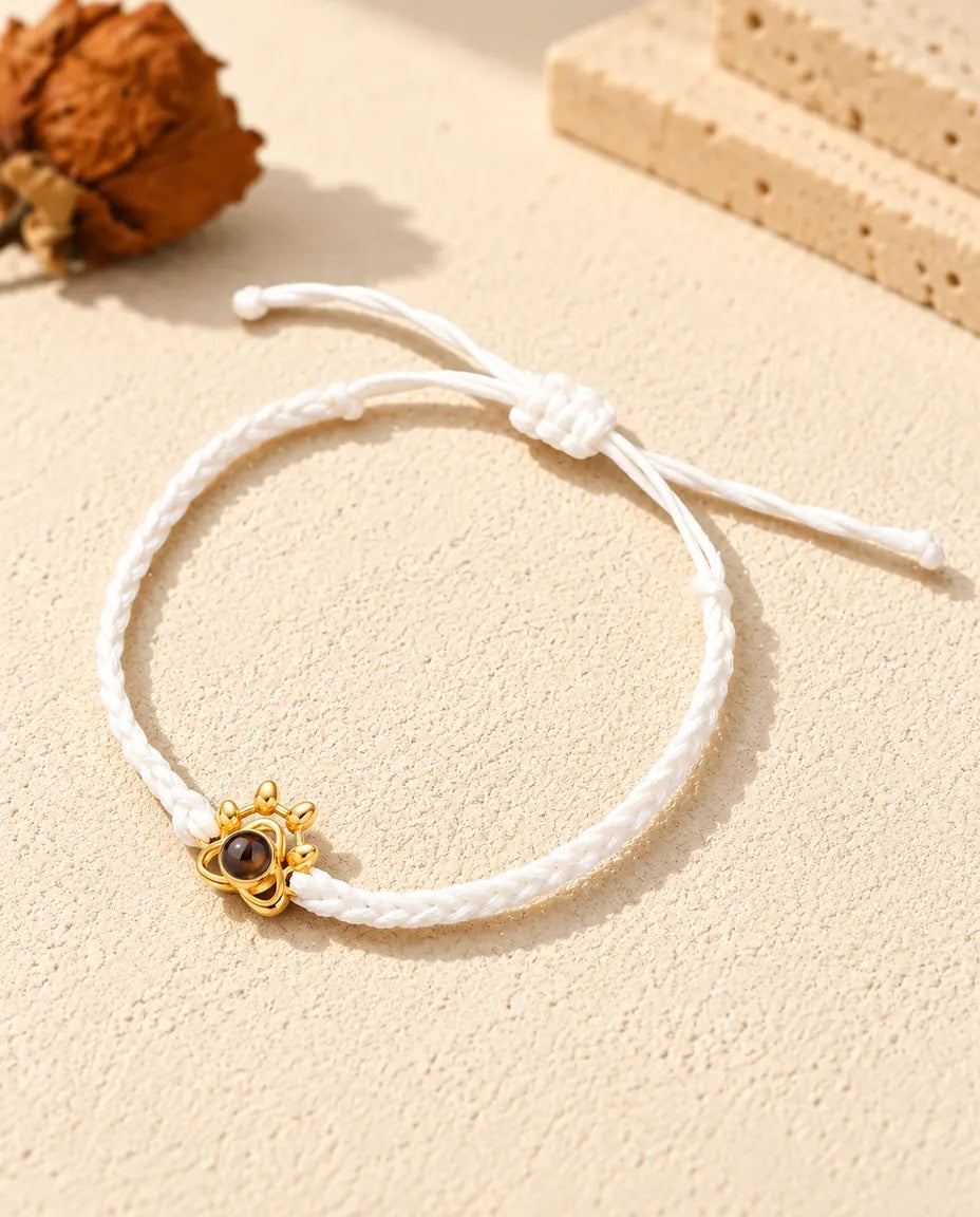 Armband met foto erin aan een wit gevlochten koord met goudkleurig pootje en schuifknoop