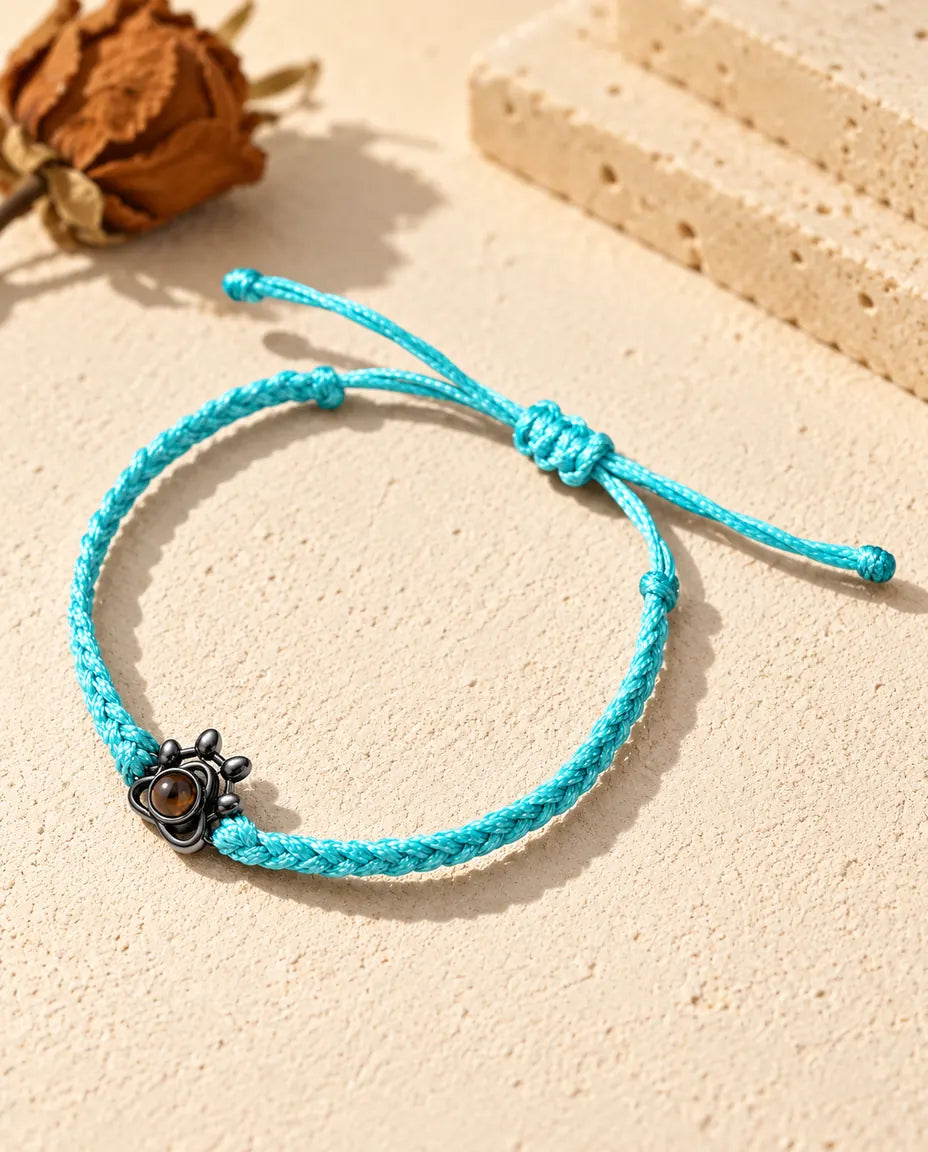 Zwart pootje aan een blauw gevlochten koord, met een bruin projectiesteentje als voetkussentje