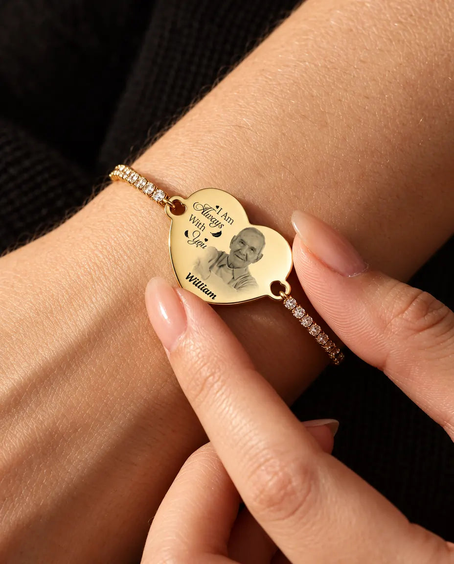 Vingertoppen houden het goudkleurige gegraveerde fotohart vast, met de armband om de pols