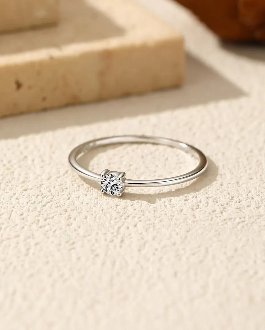 Fijne Moissanite Ring in 925 Sterling Zilver - plat liggend op een licht gestructureerd oppervlak
