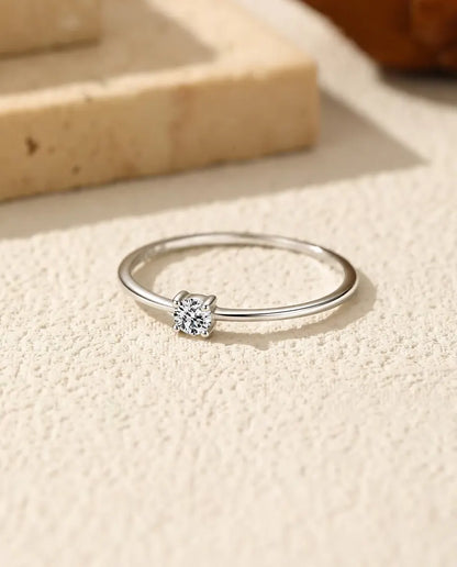 Fijne Moissanite Ring in 925 Sterling Zilver - plat liggend op een licht gestructureerd oppervlak