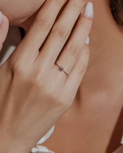 Fijne Moissanite Ring in 925 Sterling Zilver - gedragen door een model met haar handen bij haar gezicht