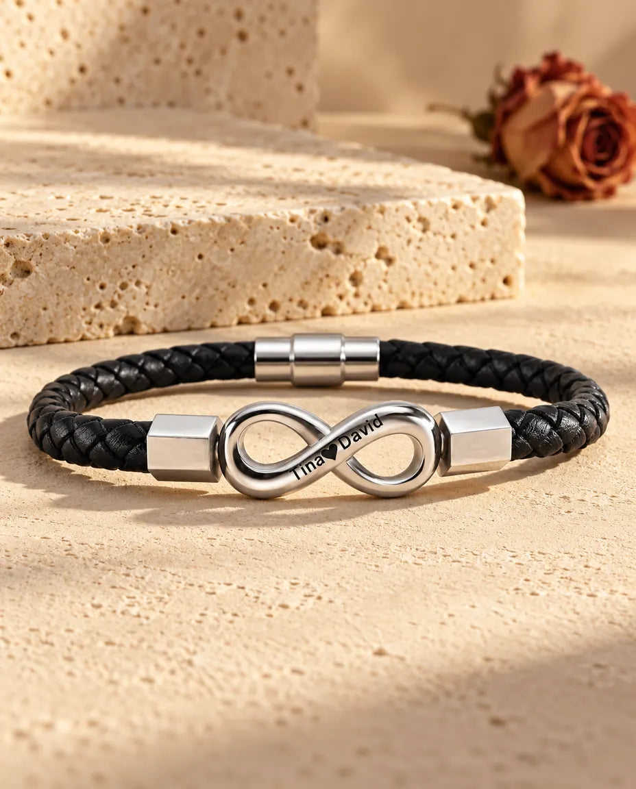 Zilverkleurig oneindigheidsteken van roestvrij staal met zeshoekige eindkapjes op een zwarte armband van gevlochten kunstleer