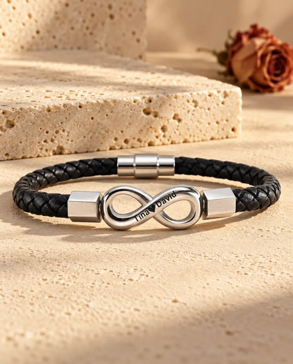 Zilverkleurig oneindigheidsteken van roestvrij staal met zeshoekige eindkapjes op een zwarte armband van gevlochten kunstleer