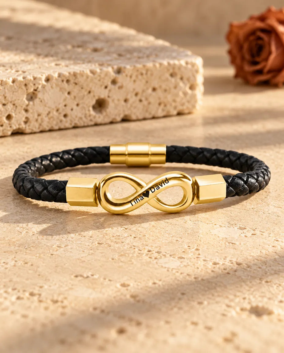 Goudkleurige gegraveerde herenarmband met oneindigheidsteken op een zwart koord van gevlochten kunstleer