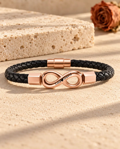 Roségoudkleurig gegraveerd oneindigheidsteken op een zwarte armband van gevlochten kunstleer
