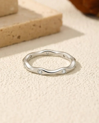Golvende Moissanite Ring in 925 Sterling Zilver - plat liggend op een licht gestructureerd oppervlak