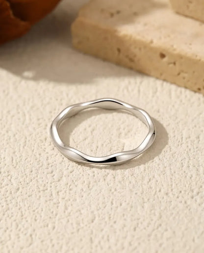 Golvende Ring in 925 Sterling Zilver - plat liggend op een licht gestructureerd oppervlak