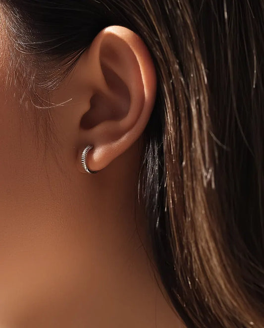 Huggie Creolen met Ribbels in 925 Sterling Zilver - gedragen in het oor van een model, close-up