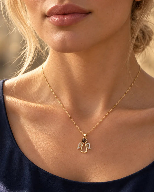 Vrouw in een donkerblauwe top draagt de goudkleurige ketting met engeltje en foto erin